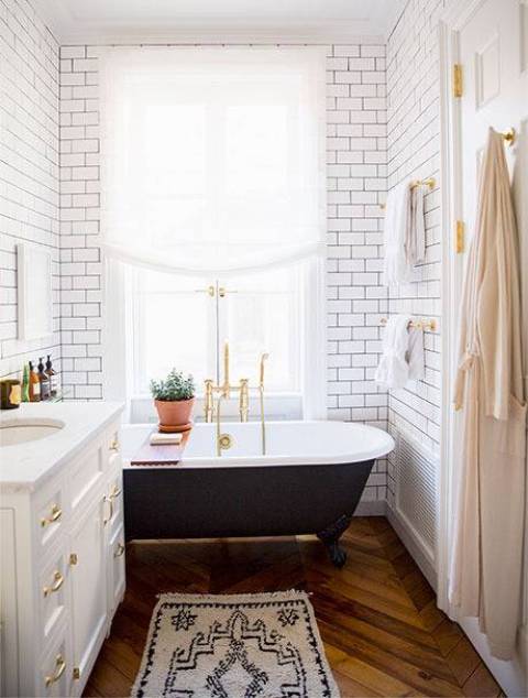 The bathroom is mid-century modern with subway tiles, chevron wooden floors and a free-standing bathtub