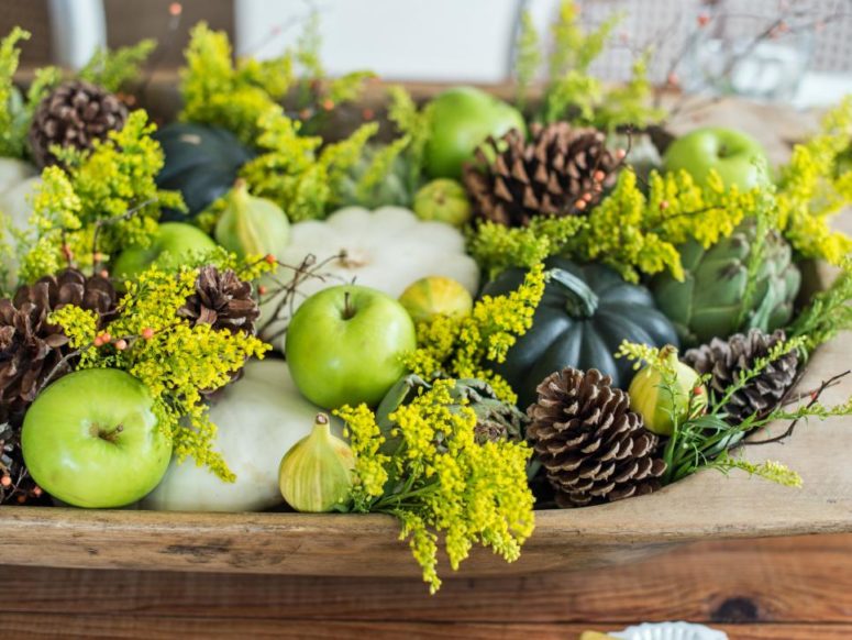 seasonal pumpkins, gourds, pinecones and flowering branches in a wooden bowl