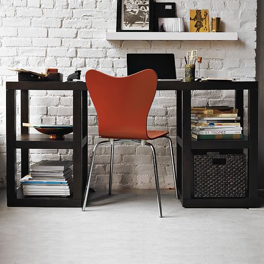rough white brick contrast with a black desk and an orange chair