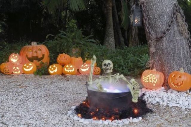 yard haunt with a skeleton in a cauldron and jack-o-lanterns