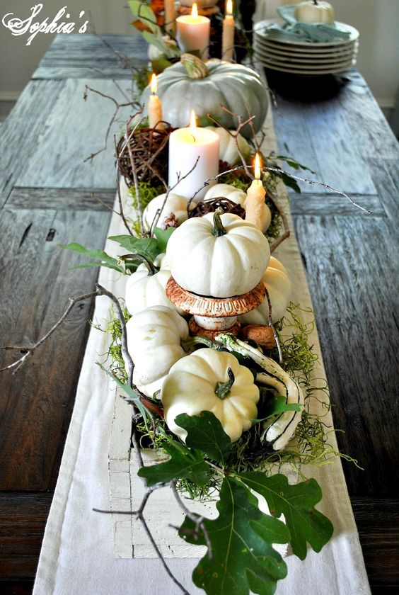 centerpiece with white pumpkins, moss, leaves and candles is refreshing
