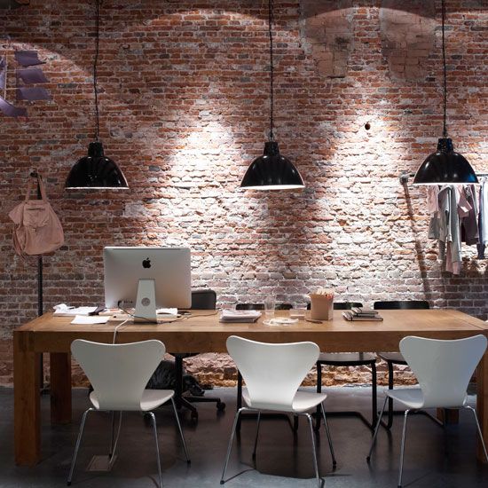 a minimalist home office is accentuated with rough brick