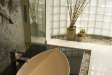 27 rough stone wall and pebbles on the floor give an Asian feel to this bathroom