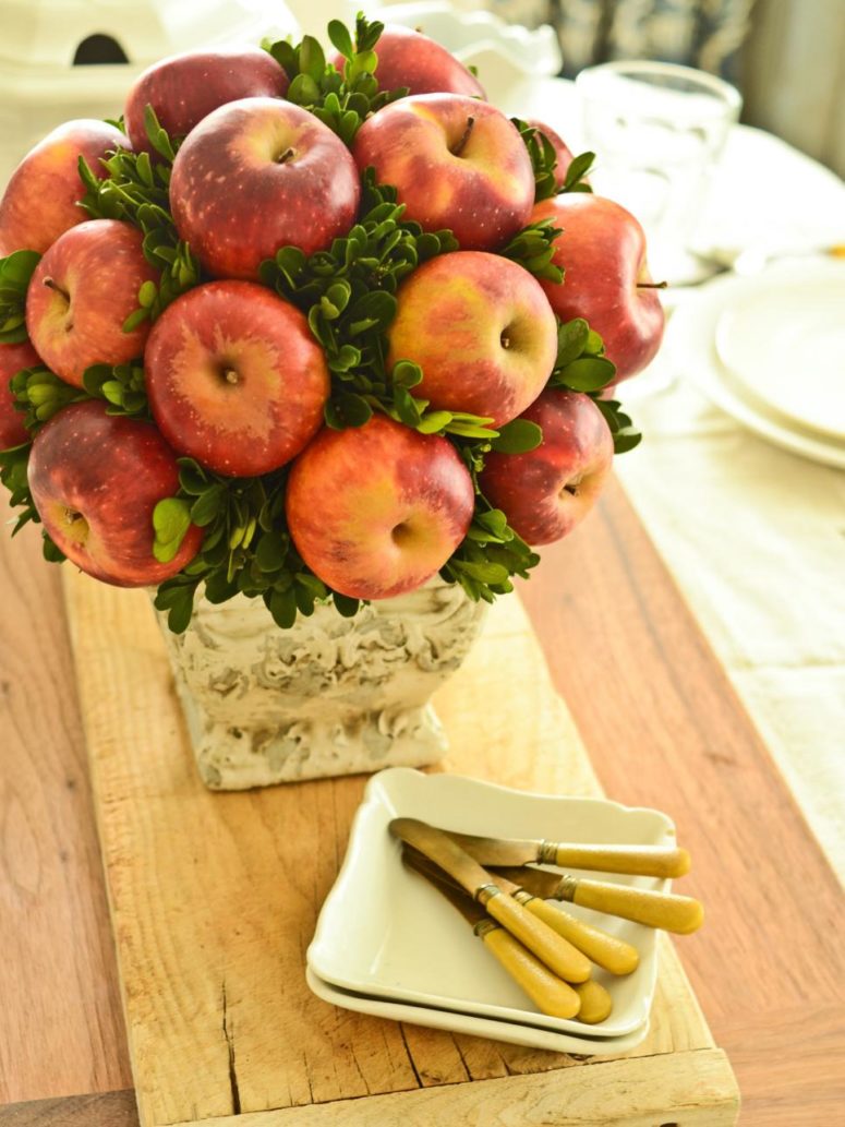 foam topiary form in a vase with sprigs of fresh greenery and apples