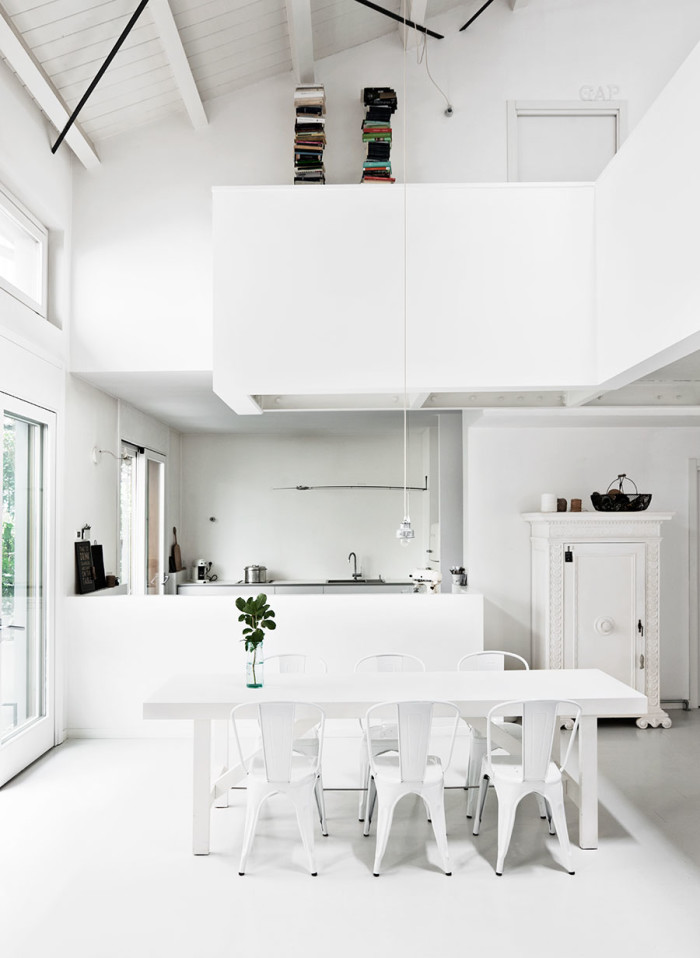 The kitchen is white and serene, it gets an advantage from the double height windows, they show the patio and bring much light in