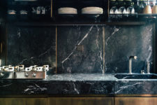 03 The kitchen is clad in black marble and dark wood, it looks modern and luxurious