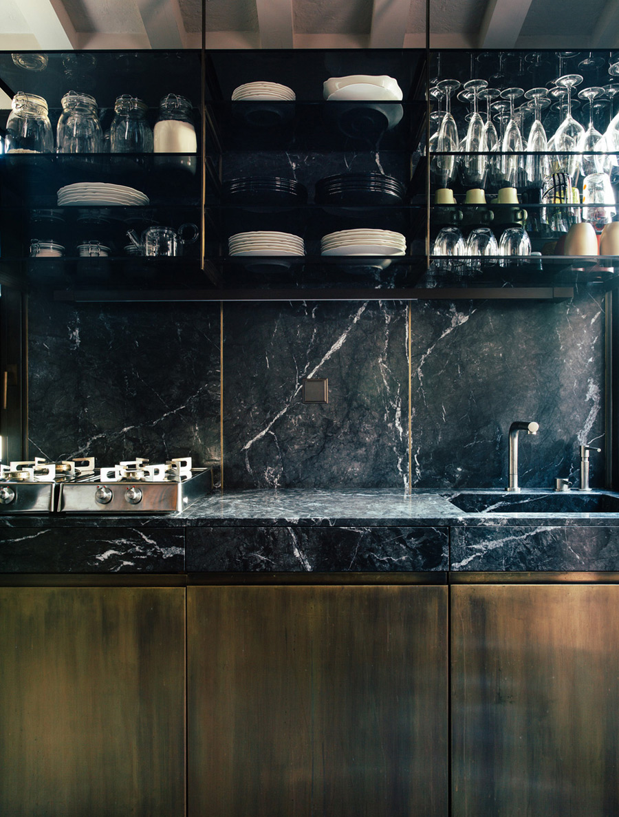 The kitchen is clad in black marble and dark wood, it looks modern and luxurious