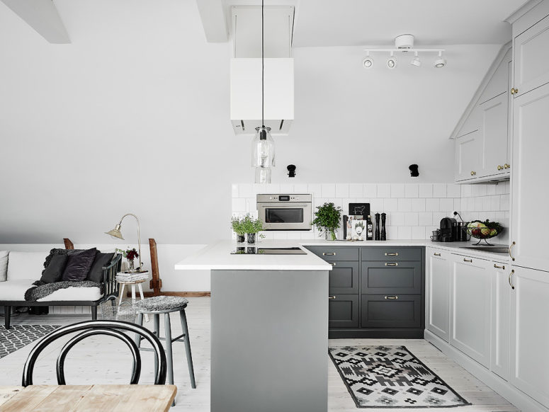 The kitchen is modern, with grey and white cabinets and greenery to enliven the look