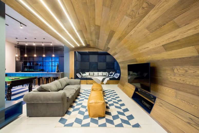 There's a TV area with a cool sofa and some leather ottomans, and a folding wooden ceiling is gorgeous