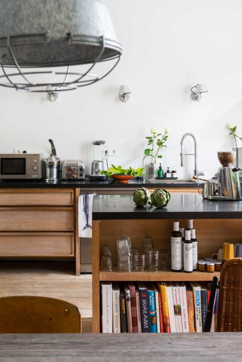 sleek kitchen The kitchen features sleek black surfaces, wooden cabinets and floor, it's filled with light and not as whimsy as other areas. The kitchen island features some storage space.