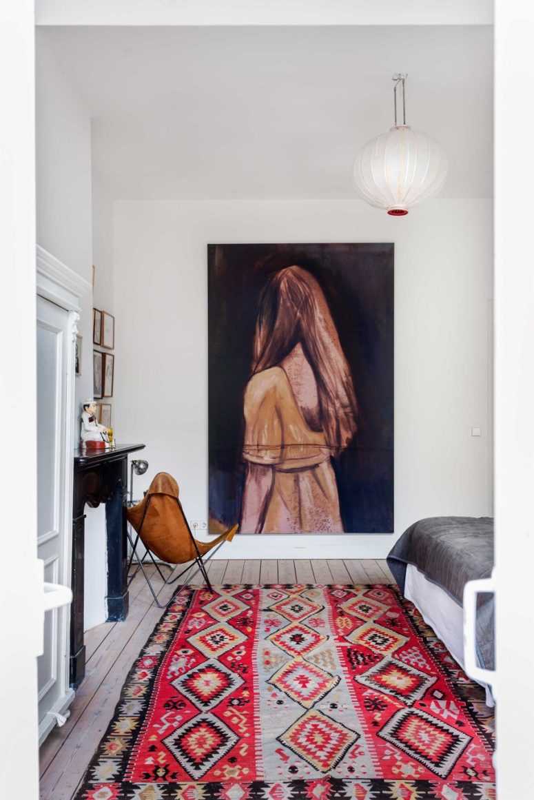 boho bedroom The bedroom boasts of colorful boho textiles, artworks, a black fireplace and a mid-century leather chair