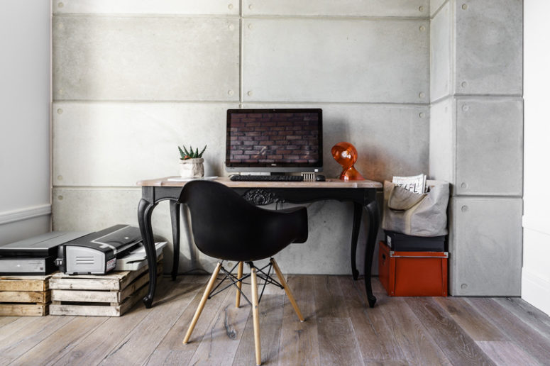 The home office is small, with concrete paneling, pallet storage and a vintage desk