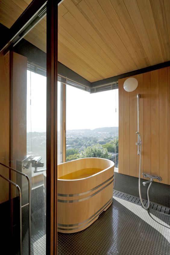 dark tile floors and light woods for a bathroom with a stunning views and a custom-order Japanese umbrella pine bathtub