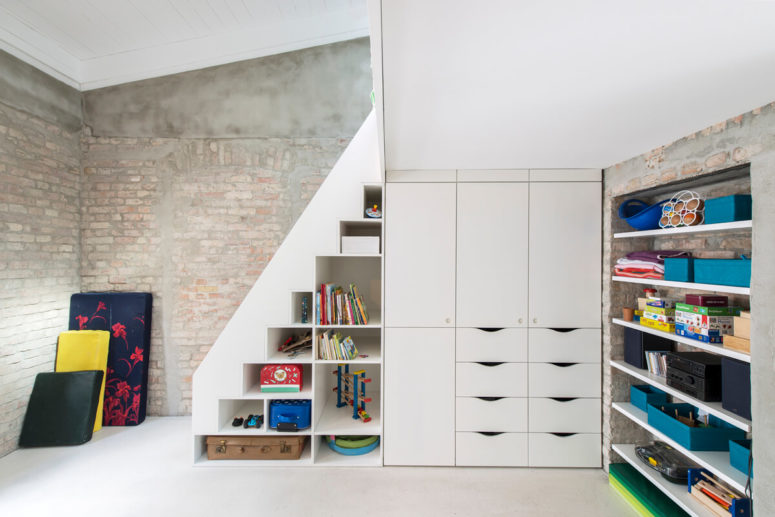 The kid's playspace has a lot of storage cabinets and shelves and a private bedrom area above the stairs