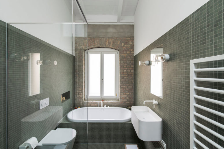 The bathroom is clad with green tiles, it's small but still has a fireplace in front of the bathtub