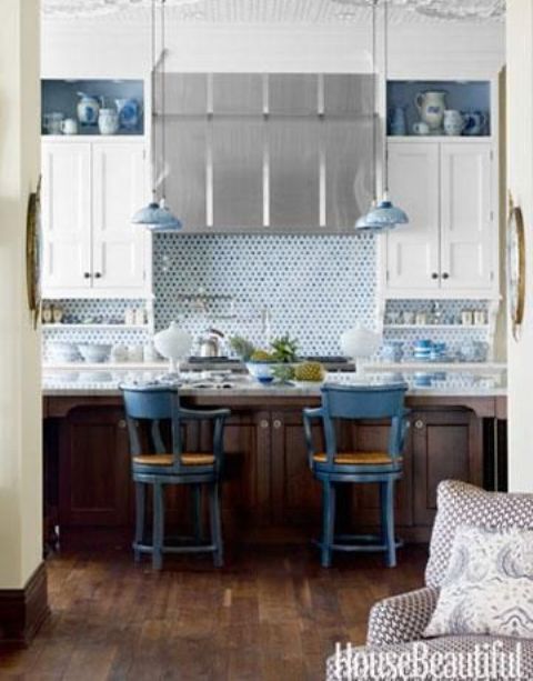 blue penny tile and delft pottery lend a watery inluence to this kitchen with white cabinets and stainless steel hood