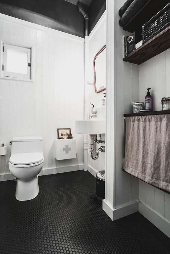 monochromatic bathroom with black penny tiles on the floor