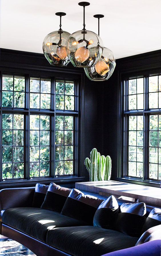 dark hued room with purple accents, cact and unique pendants