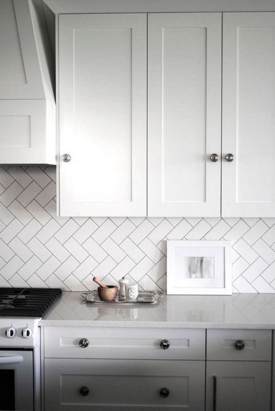 a kitchen backsplash clad in subway tiles with a diagonal herringbone pattern is a cool way to add interest to your space without adding color