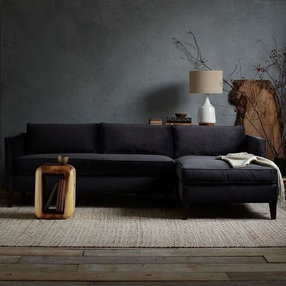 dark grey walls, a black sofa and raw wood furniture for a natural feel