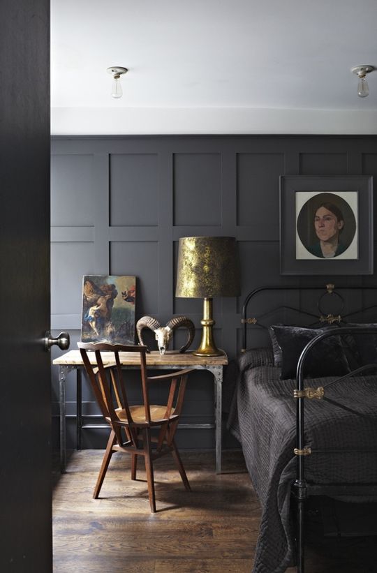 a moody Gothic bedroom with gold touches and vintage furniture, with vintage artwork and an animal skull