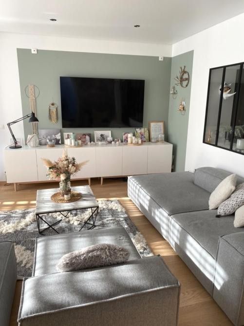 a Scandinavian living room with a green accent wall, aTV unit with decor, a low grey sofas and loungers, a coffee table