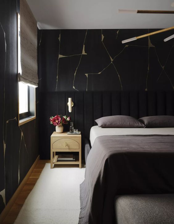 a beautiful and chic moody bedroom with catchy wallpaper, a black bed with an extended headboard, grey bedding, neutral nightstands