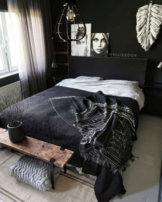 a contemporary moody bedroom with black walls, black furniture and a wooden bench, pendant lamps and art