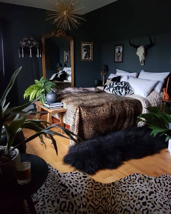 a glam moody bedroom with wooden furniture, an oversized mirror in a gold frame, a sunburst chandelier, faux animal skis