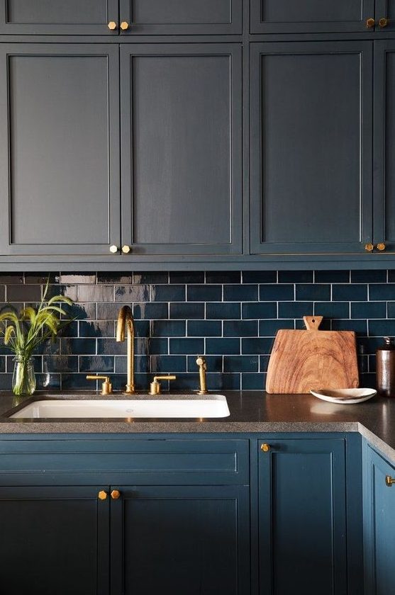 a matte navy kitchen with navy subway tiles and gold touches for a bold and dramatic kitchen in dark shades