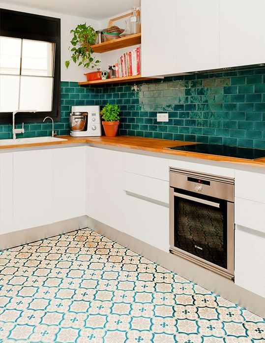 a modern white kitchen with an emerald subway tile backsplash and butcherblock countertops and open shelves