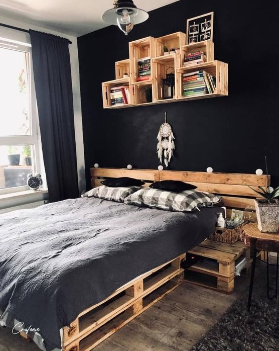 a moody industrial bedroom with black walls, pallet furniture and boho decor and plants is very bold and chic