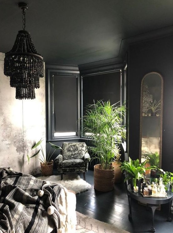 a refined black bedroom with a bay window, a black beaded chandelier, potted plants, faux fur and an arched mirror