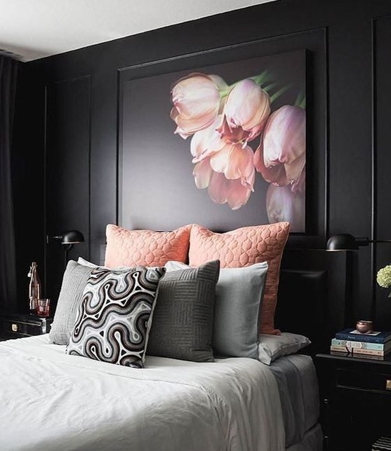 a refined moody bedroom with black walls, black furniture, pink and grey bedding and a pink floral artwork