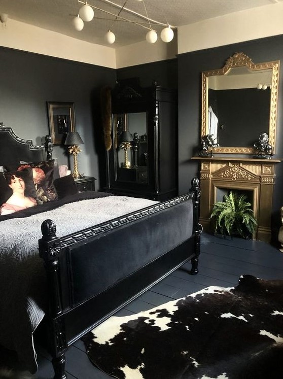 a sophisticated bedroom with black walls, a black bed and mirror, a gold fireplace and a mirror and some plants and art