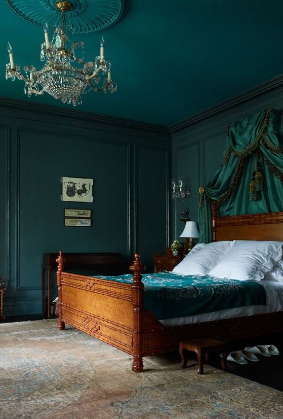 a sophisticated bedroom with dark green walls and a ceiling, a green canopy and bedding is moody and chic