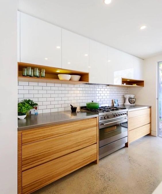a trendy two-tone kitchen with white and stained cabinets, a white subway tile backsplash and metal countertops
