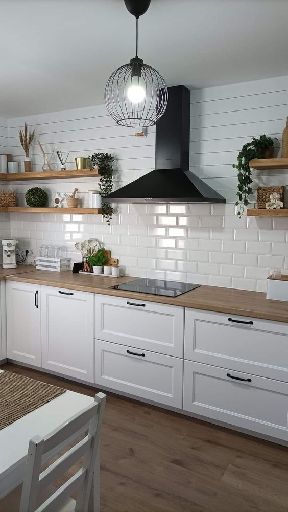 a white Nordic kitchen with shaker cabinets, a white subway tile backsplash, open shelves and a black hood