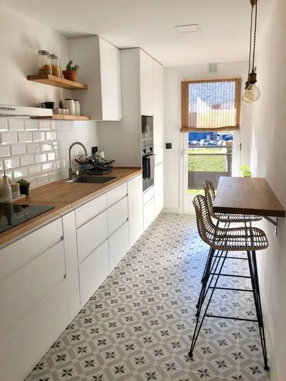a white Scandinavian kitchen with buctherblock countertops, a white subway tile backsplash and a wall-mounted table and stools