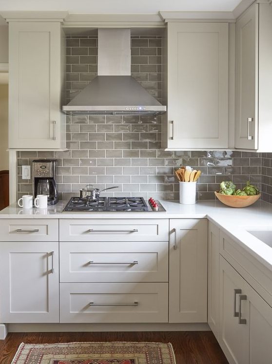 a white farmhouse kitchen with light grey subway tile backsplash and stainless steel to finish off the look