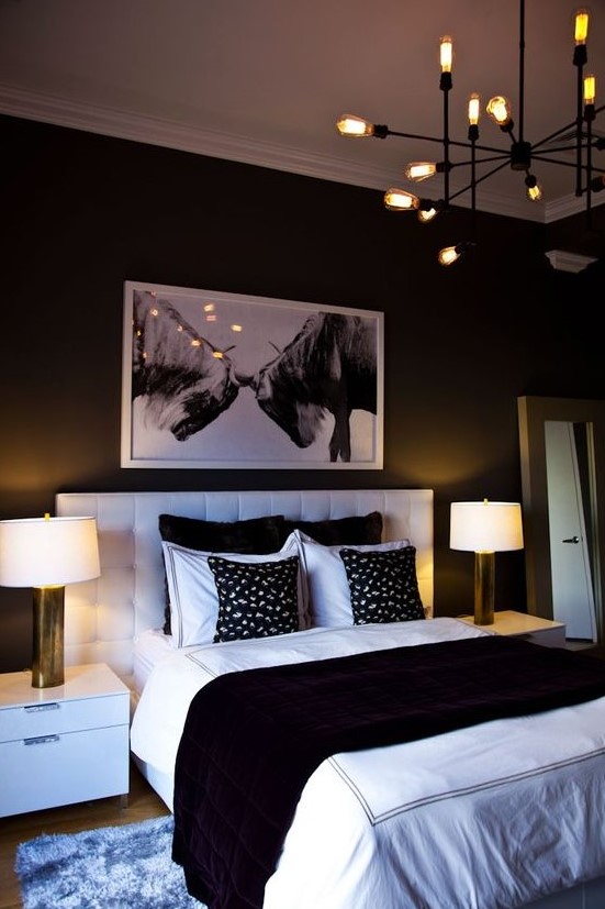 an elegant contemporary bedroom with a white upholstered bed, white nightstands, a chic chandelier and an artwork