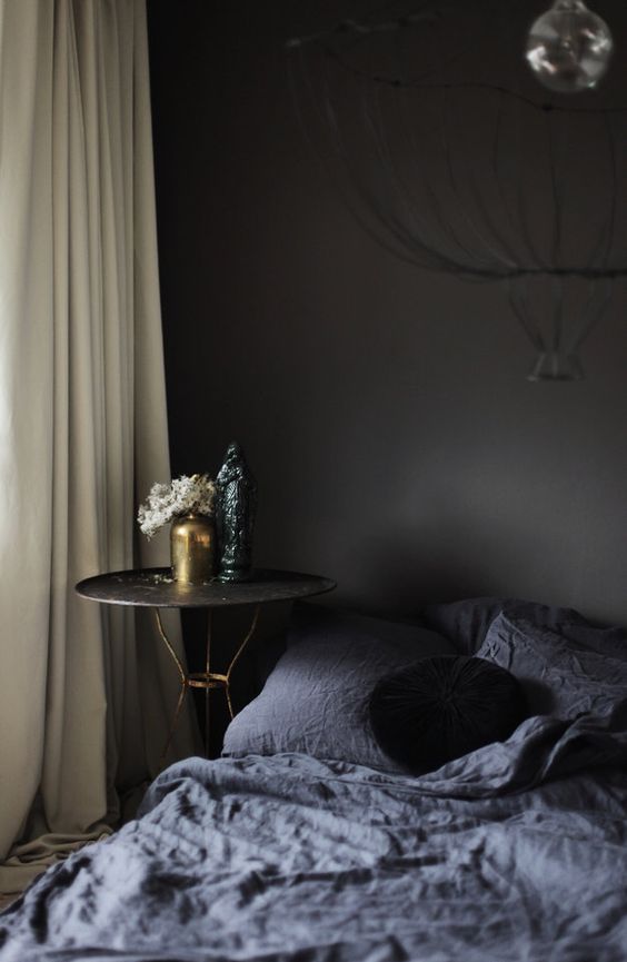 black walls, graphite bedding and a refined nightstand with gold legs