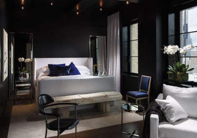 an elegant dark bedroom with a crispy white bed and a raw wood bench for a contrast, lights and mismatching chairs 25+ Romantic Dark & Cozy Bedroom Ideas