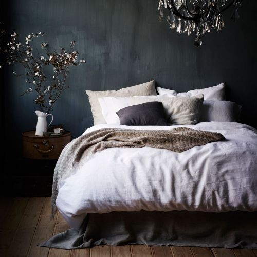 a moody bedroom with dark grey walls and stained wood furniture plus a chic chandelier looks very relaxing and very stylish