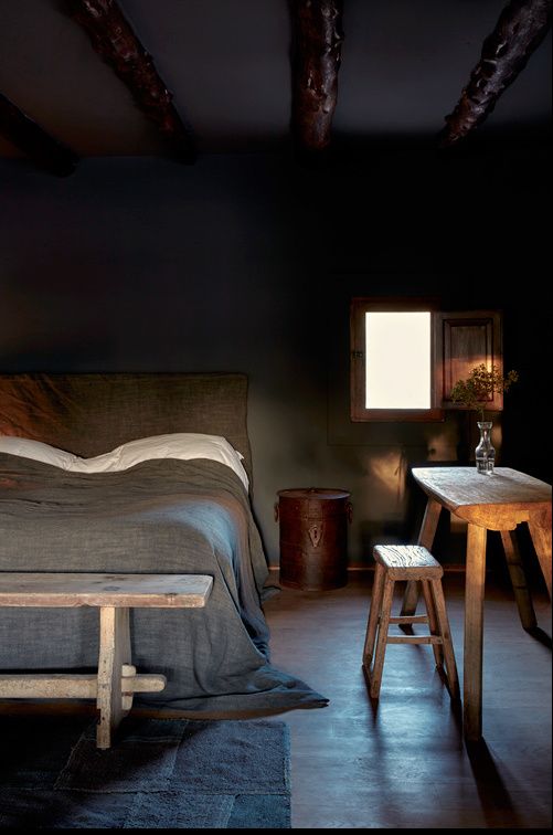 rustic bedroom decor with dark walls, upholstered bed and rough wooden furniture