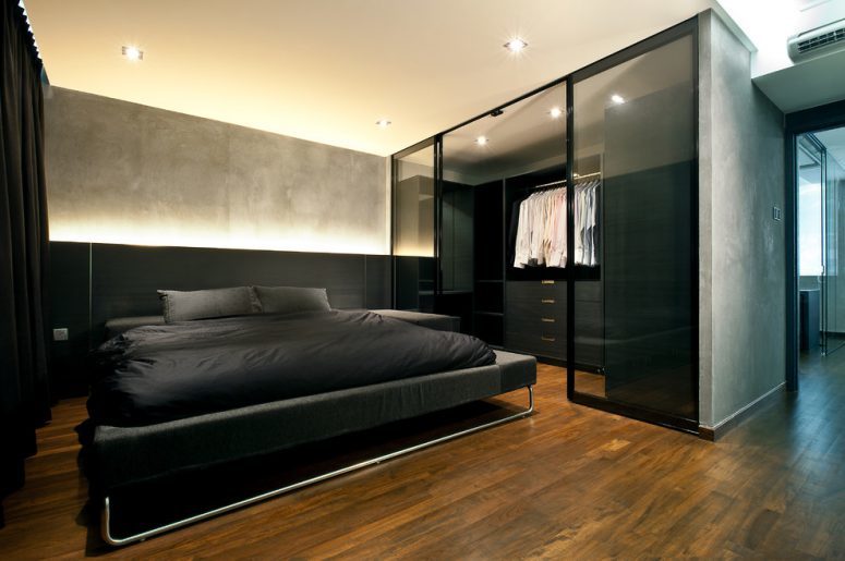 urban bedroom with gray walls and a walk-in closet behind glass doors