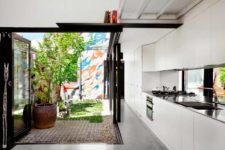 02 The kitchen is done in white, it’s modern and functional and the space is extended outdoors to the sunlit backyard