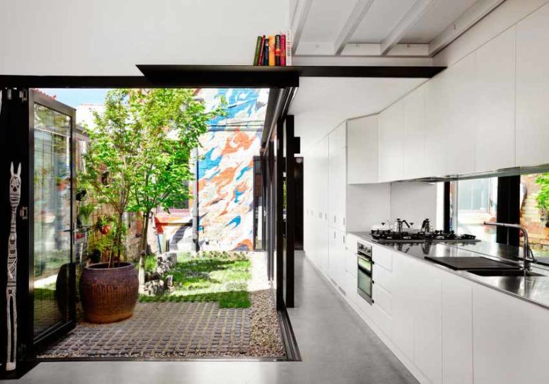The kitchen is done in white, it's modern and functional and the space is extended outdoors to the sunlit backyard The kitchen is done in white, it's modern and functional and the space is extended outdoors to the sunlit backyard