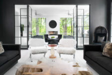 02 The living room has graphite grey walls and furniture, a large nautral-shaped wooden coffee table and fur-covered chairs
