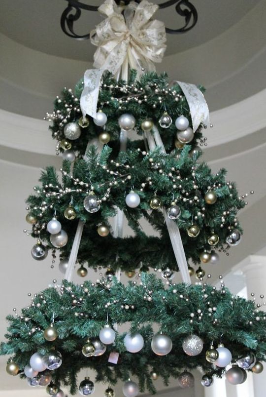 a chandelier made of faux evergreen wreaths and silver and gold ornaments